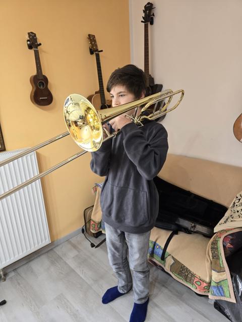 Ein Jugendlicher spielt zuhause Posaune.